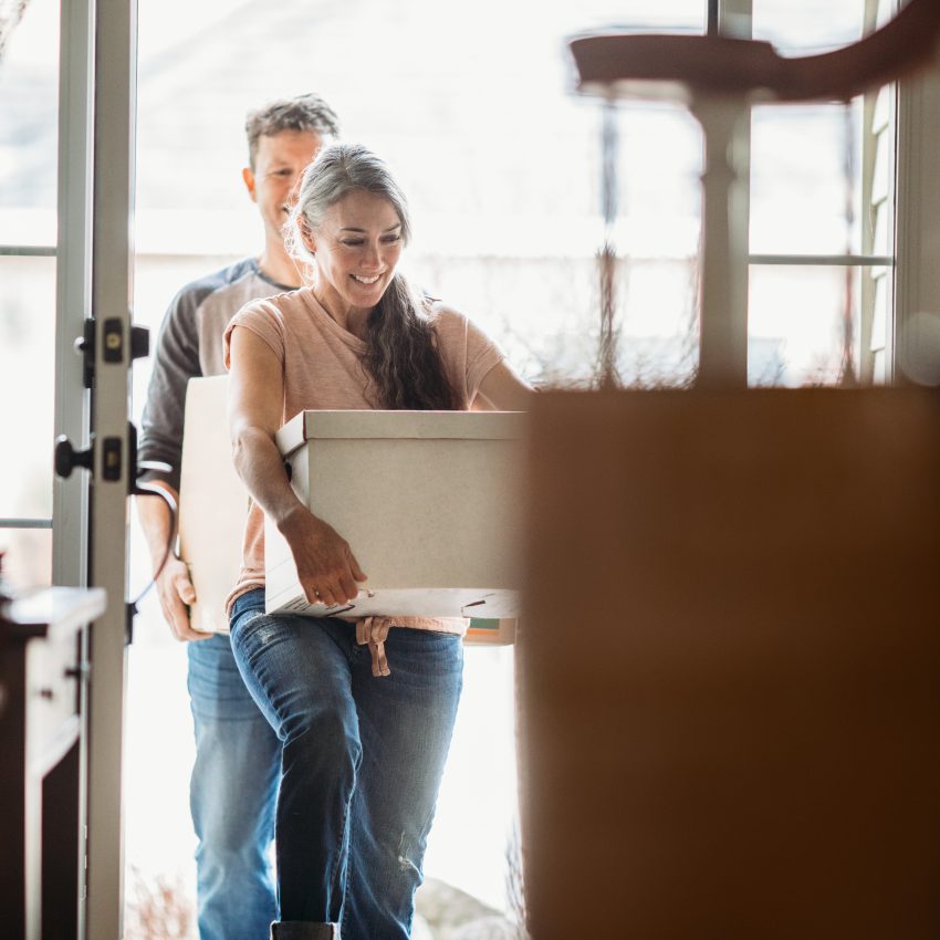 A couple in their 50's moves in to their new home, unpacking boxes and enjoying the time together.  Could also depict moving out of a home.