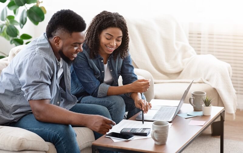 A couple is smiling while they see how much they can save with a mortgage refinance.